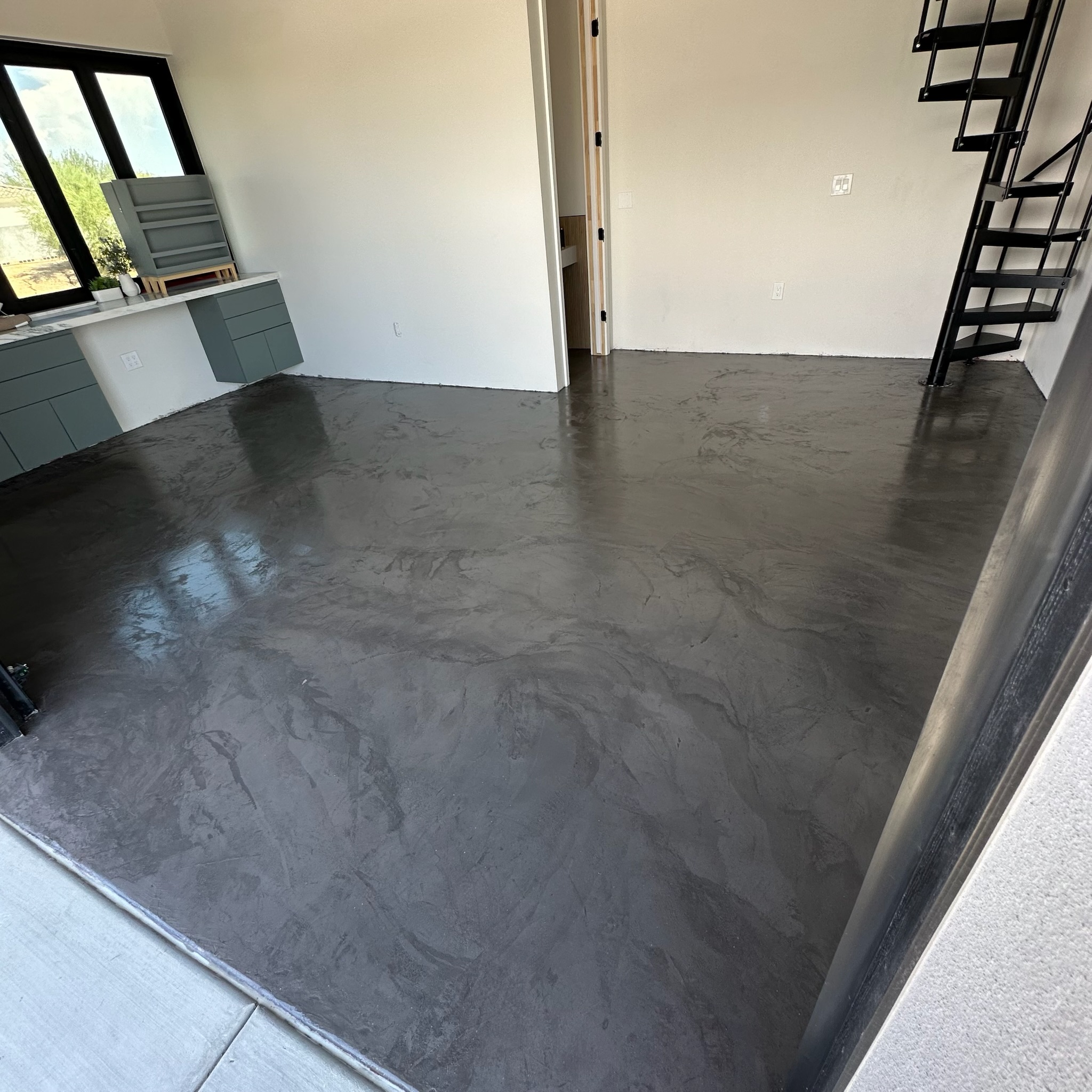 Dark microcement floor with modern spiral staircase by Tru Coat Epoxy
